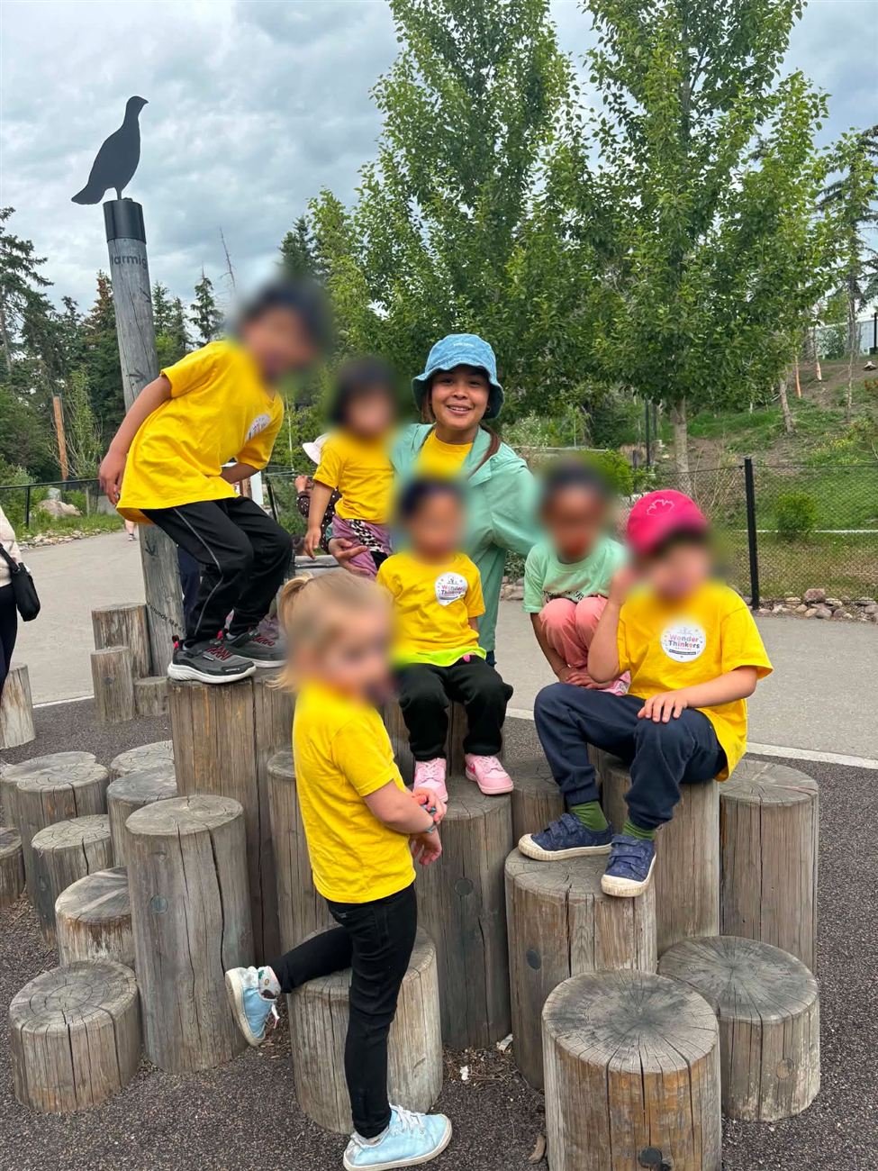 Wonder Thinkers children in matching yellow shirts playing together outdoors on a nature playground